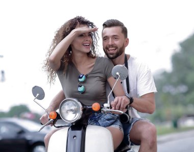 Güzel genç bir çift bir scooter sürme sırasında gülümsüyor