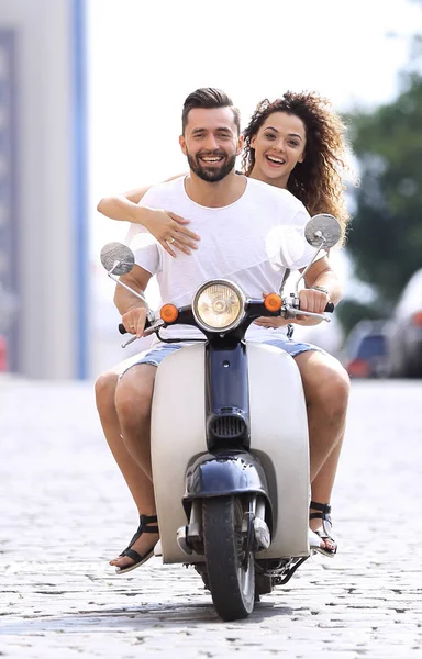 Feliz joven pareja montando un scooter en la ciudad en un día soleado — Foto de Stock