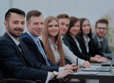 Kendine güvenen işadamı meslektaşları arasında kamera bakıyor