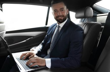 Arabanın içinde otururken dizüstü klavye üzerinde işadamı