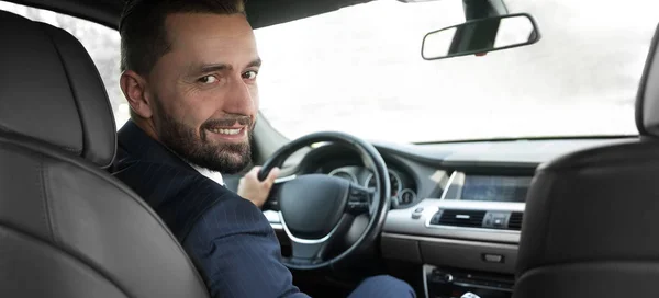 Businessman sitting at the wheel of a prestigious car — Stock Photo, Image