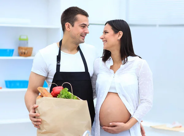 Husband and his pregnant wife are combing through the pack,standing in the kitchen — Stock Photo, Image