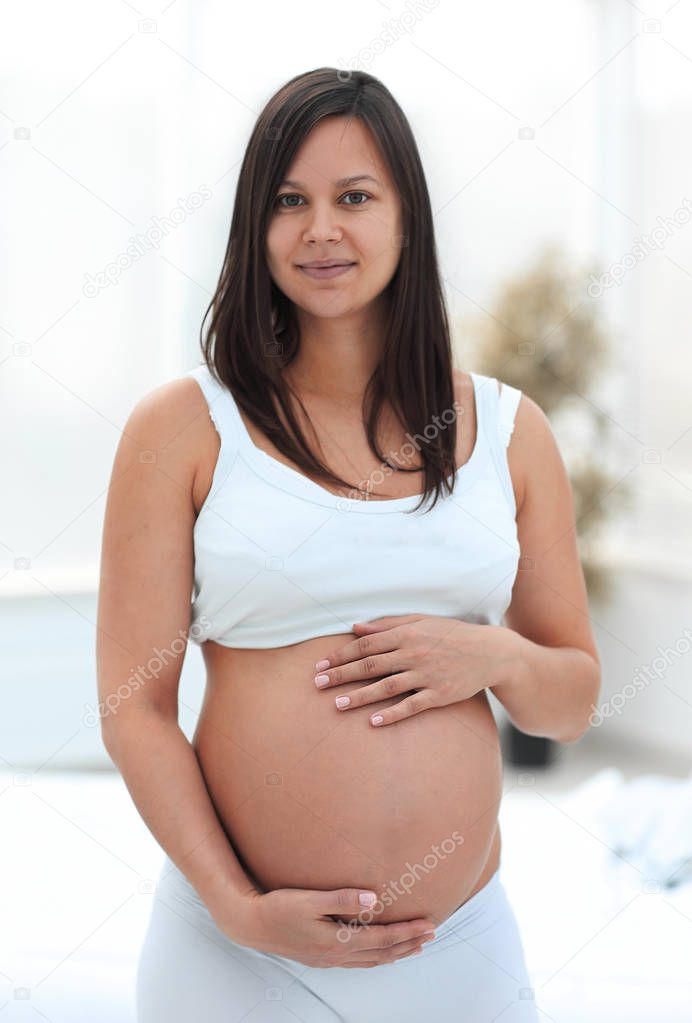 portrait of young pregnant woman on a light background.