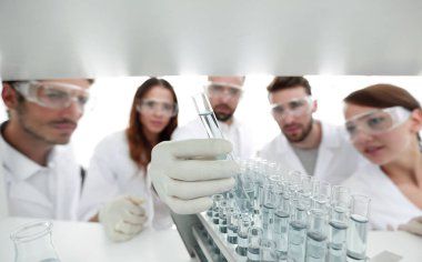 arka plan görüntüsü sıvı cam tüp içinde eğitim microbiologists oluşan bir gruptur.
