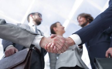 İş ortaklarının el sıkışması ön planda.