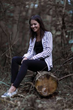 Ormanın içinde bir günlük üzerinde oturan genç kadın.