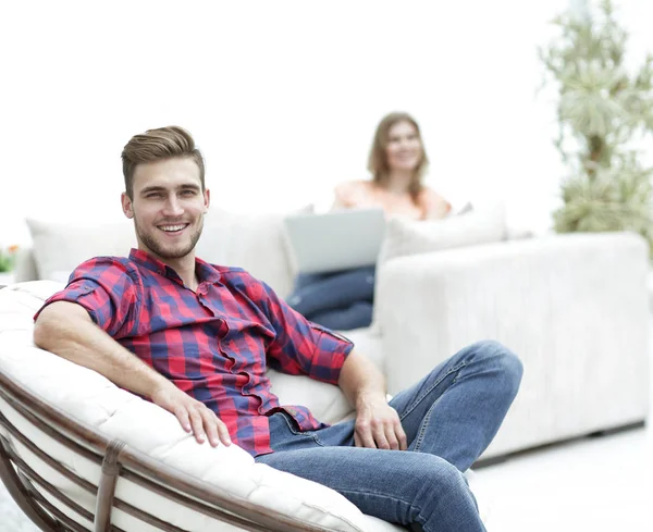 Sonriente joven macho sentado en una silla grande —  Fotos de Stock