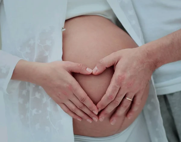 Femme enceinte tenant ses mains en forme de coeur sur son bébé bu — Photo