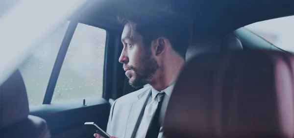 Feliz joven hombre de negocios utilizando el teléfono móvil en el asiento trasero del coche — Foto de Stock