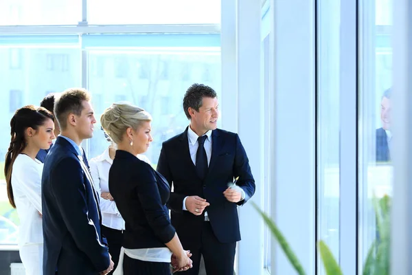 Gruppe von Geschäftsleuten schaut aus dem Fenster und steht in der Lobby des Büros. — Stockfoto