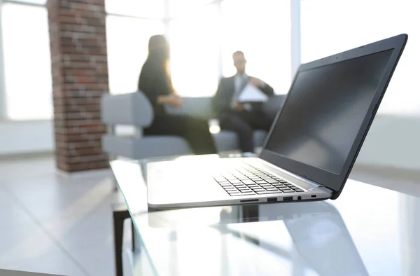 Concéntrate en el portátil sobre la mesa. Personas borrosas en el fondo . — Foto de Stock