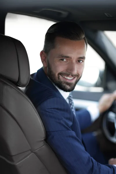 Handsome young man sitting in the front seat of a car looking at the camera — Stock Photo, Image
