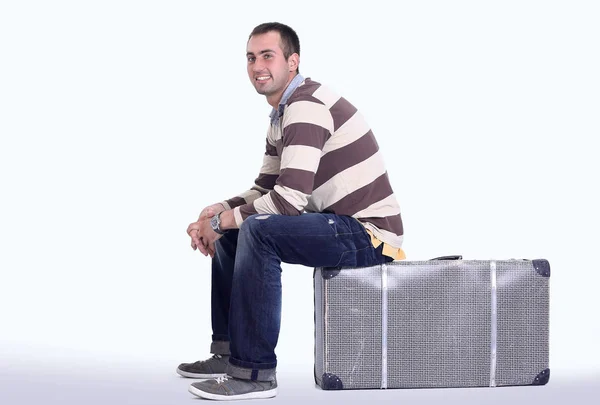 Young man sits on the big suitcase — Stock Photo, Image