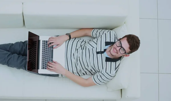 Visão superior do jovem feliz usando seu laptop em vida brilhante ro — Fotografia de Stock