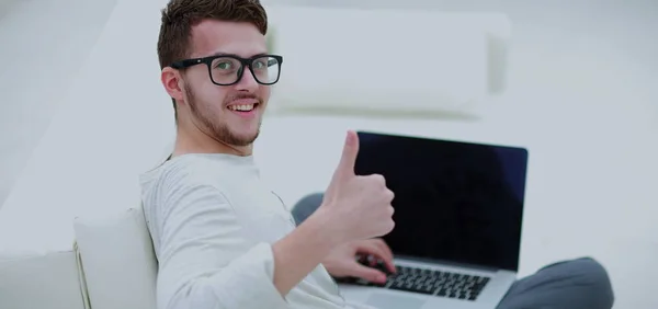 Молодой человек использует свой ноутбук и показывает большой палец вверх. Закрыть . — стоковое фото