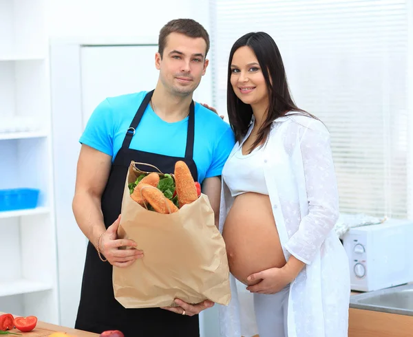 Husband and pregnant wife holding a package of baguettes — Stock Photo, Image