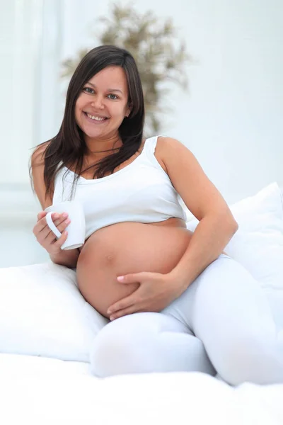 Glad gravid kvinna sitter i vardagsrummet — Stockfoto