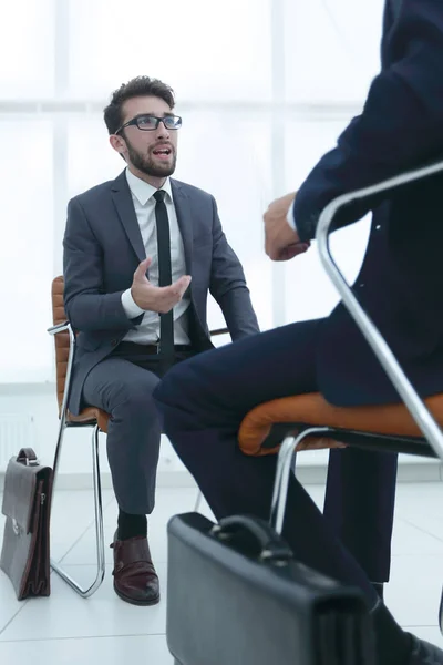 Чоловік сидить на стільці в офісі слухає бізнесмена — стокове фото