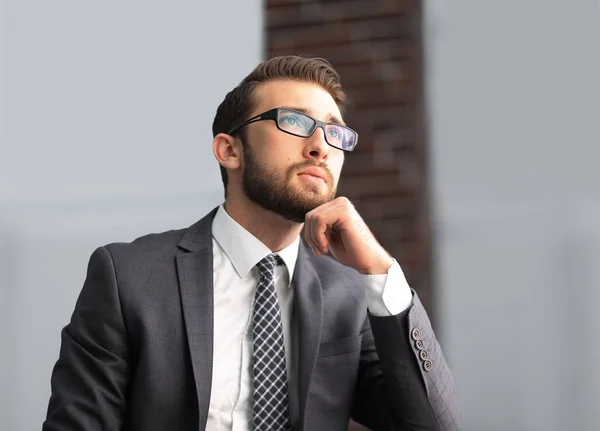 Knappe zakenman denkt, zittend op de bank in zijn kantoor — Stockfoto