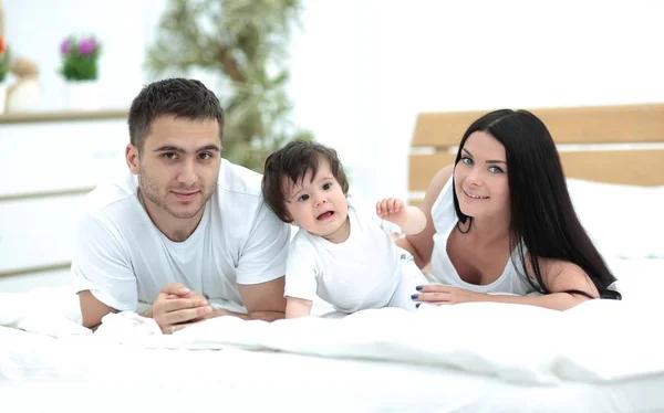 Retrato de familia joven y feliz acostados en la cama juntos —  Fotos de Stock