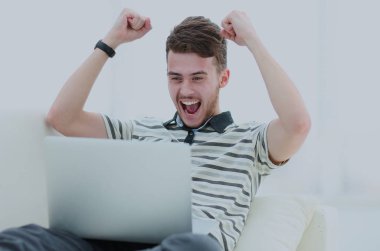 Diz üstü parlak oturma odasında kullanan mutlu genç adam.