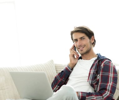 cep telefonu üzerinde konuşurken laptop ile ciddi genç adam