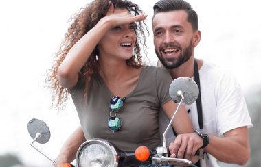 Güzel genç bir çift bir scooter sürme sırasında gülümsüyor