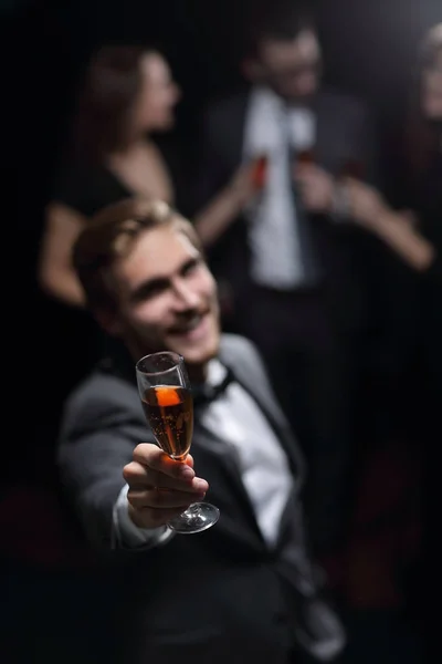 Stylowy młody człowiek stojący przy kieliszku szampana. — Zdjęcie stockowe