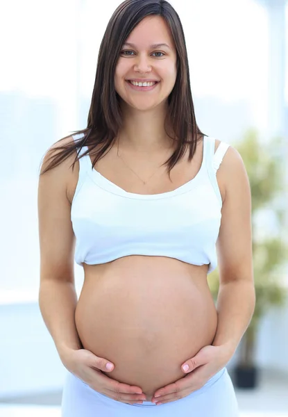 Крупный план беременной женщины, кладущей руки на животик . — стоковое фото