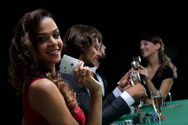 Jovem morena mulher jogar poker no fundo preto — Fotografia de Stock