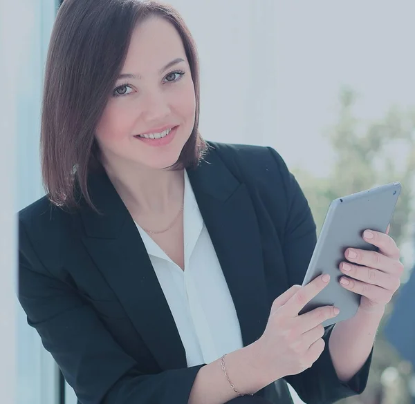 Szczęśliwa młoda kobieta za pomocą cyfrowego tabletu w biurze — Zdjęcie stockowe