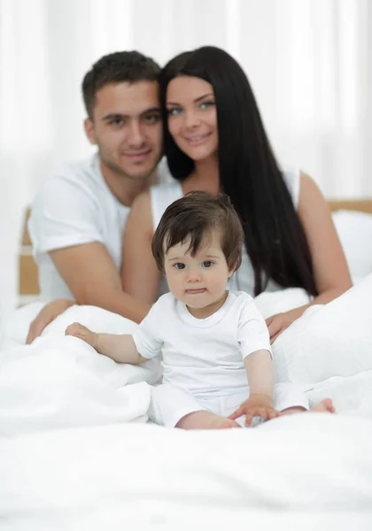 Portrait of a joyful family sitting on the bed at home — Stock Photo, Image