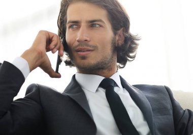 iş adamı rahat bir sandalyede otururken Smartphone'da konuşuyor.