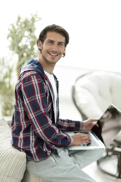 Stilvoller junger Mann, der am Laptop arbeitet und in die Kamera schaut — Stockfoto