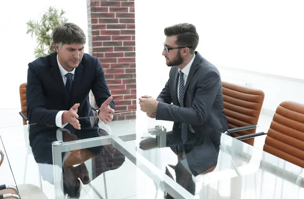 Two businessmen discussing tasks sitting at office table.