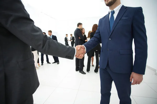 Nahaufnahme des Handschlags von Geschäftspartnern vor dem Hintergrund des Geschäftsteams — Stockfoto