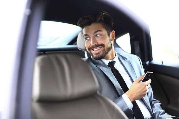 Uomo d'affari non sorridente seduto sul sedile posteriore della sua auto — Foto Stock