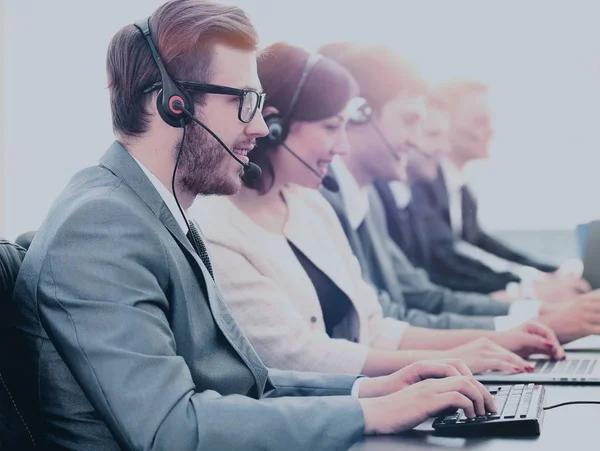 Attraktiver junger Mann, der mit seinen Kollegen in einem Callcenter arbeitet — Stockfoto