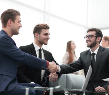 Ortaklar, takım üyelerinin huzurunda anlaşma yapıp el sıkışıyorlar.