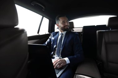 adam arabanın arka koltukta otururken dizüstü bilgisayar ile