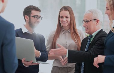 bir dizüstü bilgisayar ve iş ekibi ile gülümseyen olgun Yöneticisi