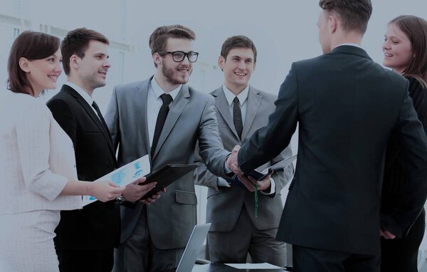 business partners in the presence of a business team shake hands