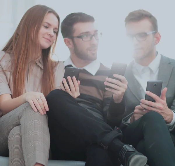 Eine Gruppe junger und glücklicher junger Menschen, die ihre Telefone benutzen und — Stockfoto