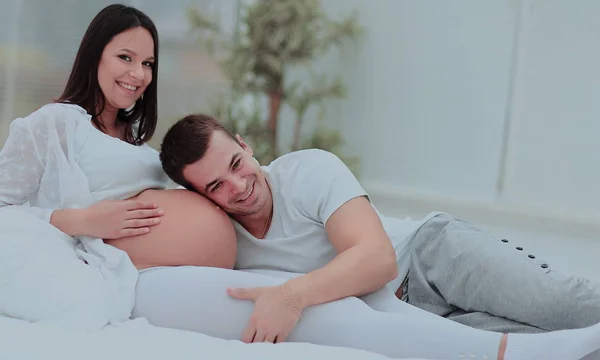 소파에서 함께 쉬고 있는 임신 한 여자와 함께 있는 부부 — 스톡 사진