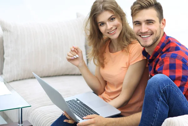 Par de estudantes com um laptop sentado no sofá — Fotografia de Stock