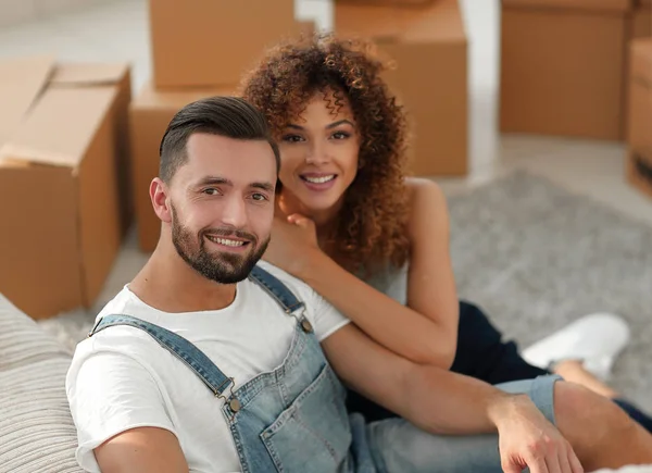 Pareja joven sentada en el suelo en un apartamento nuevo — Foto de Stock