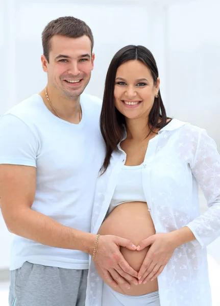 Marido e mulher grávida com as mãos dobradas na forma de um coração em sua barriga — Fotografia de Stock