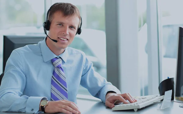 Joven feliz trabajando en el centro de llamadas, usando auriculares — Foto de Stock