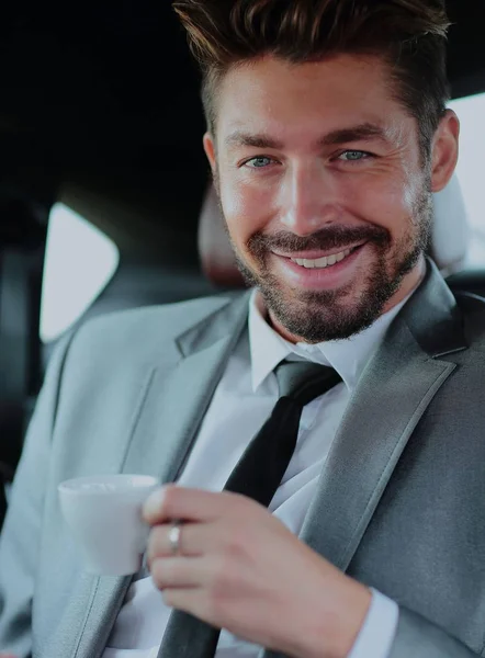 Handsome businessman having a coffee in his car — Stock Photo, Image