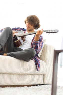Yakışıklı adam evde kanepede gitar çalmaya